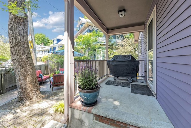 view of patio featuring fence, a grill, and covered porch