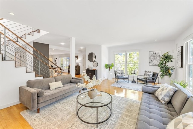 living area with healthy amount of natural light, stairway, wood finished floors, recessed lighting, and baseboards