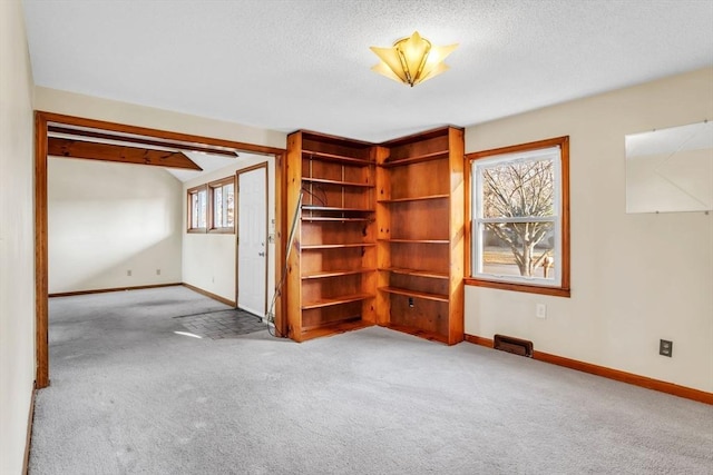 spare room featuring a textured ceiling and light carpet