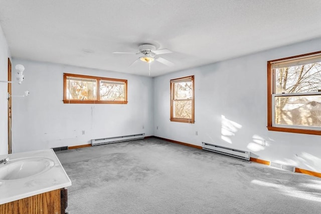 carpeted empty room featuring ceiling fan, a baseboard heating unit, and sink