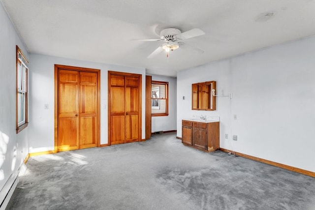 unfurnished bedroom featuring carpet flooring, multiple closets, ceiling fan, sink, and connected bathroom