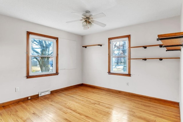 empty room featuring a wealth of natural light, ceiling fan, and light wood-type flooring