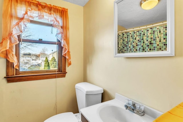 bathroom with a wealth of natural light, vanity, a textured ceiling, and toilet