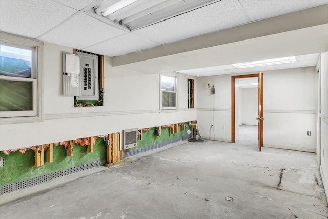 basement featuring heating unit, electric panel, and a drop ceiling