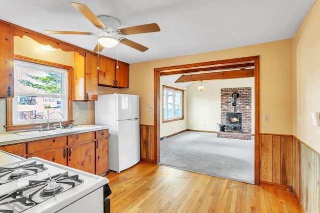 kitchen with a wood stove, plenty of natural light, white appliances, and light wood-type flooring