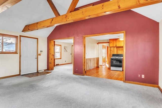 unfurnished living room with vaulted ceiling with beams, ceiling fan, and light carpet