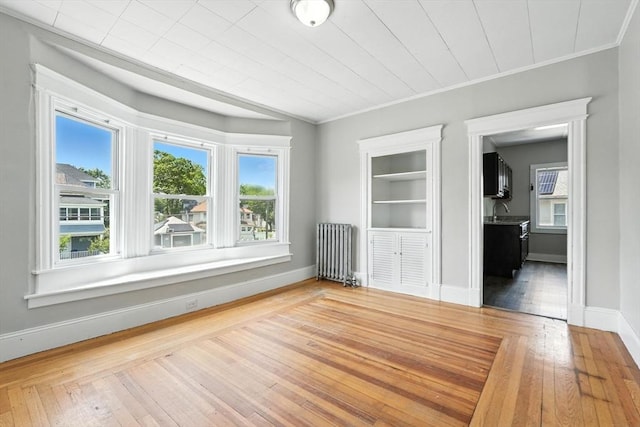 782 Sumner Ave, Springfield, MA 01108 - empty room with radiator heating unit, healthy amount of natural light, wood-type flooring, and crown molding
