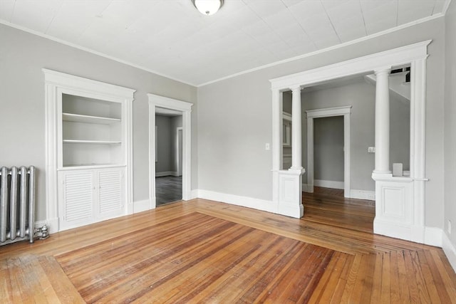 782 Sumner Ave, Springfield, MA 01108 - unfurnished room with radiator, ornamental molding, built in shelves, ornate columns, and hardwood / wood-style flooring