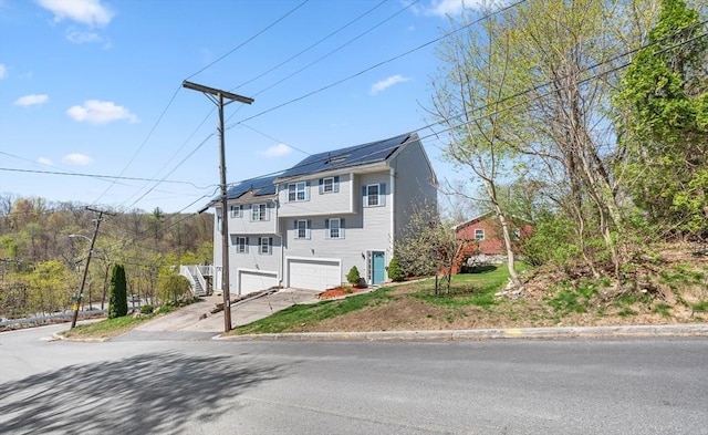 3 Clegg St, Worcester, MA 01603 - view of front facade with an attached garage, driveway, and solar panels