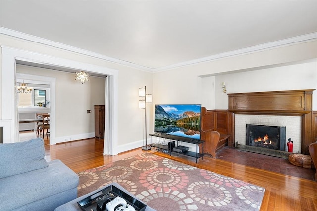 24 Central St, Somerville, MA 02143 - living room with wood-type flooring, ornamental molding, a brick fireplace, baseboards, and a chandelier