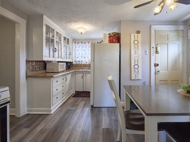 kitchen featuring dark hardwood / wood-style floors, white cabinets, hanging light fixtures, white fridge, and ceiling fan