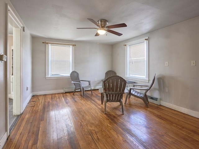 sitting room featuring baseboard heating, dark hardwood / wood-style flooring, and a wealth of natural light