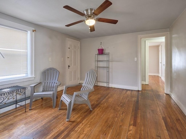 living area with dark wood-type flooring and ceiling fan