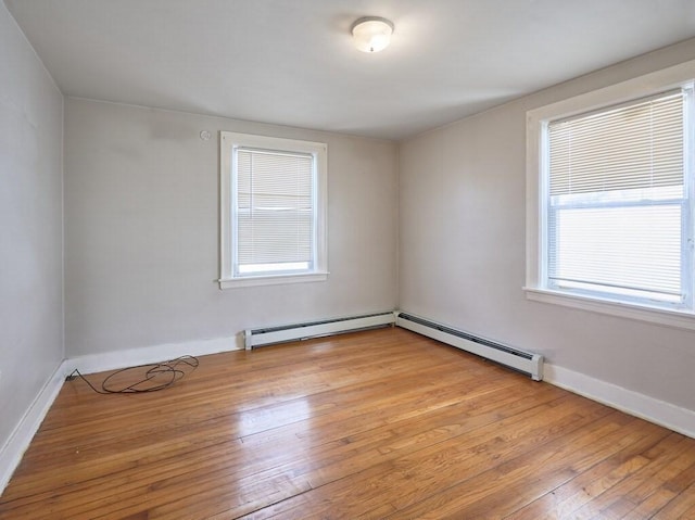 empty room featuring a baseboard heating unit and light wood-type flooring