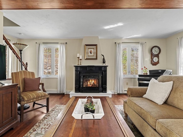 living room featuring baseboards, a glass covered fireplace, and wood finished floors