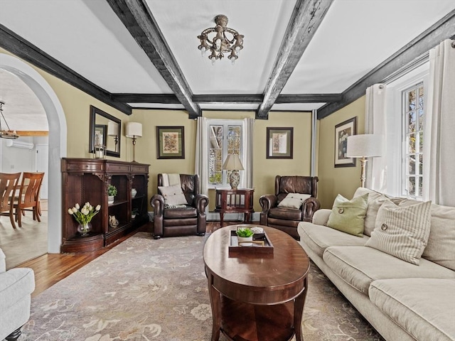 living area featuring a healthy amount of sunlight, arched walkways, wood finished floors, and a chandelier