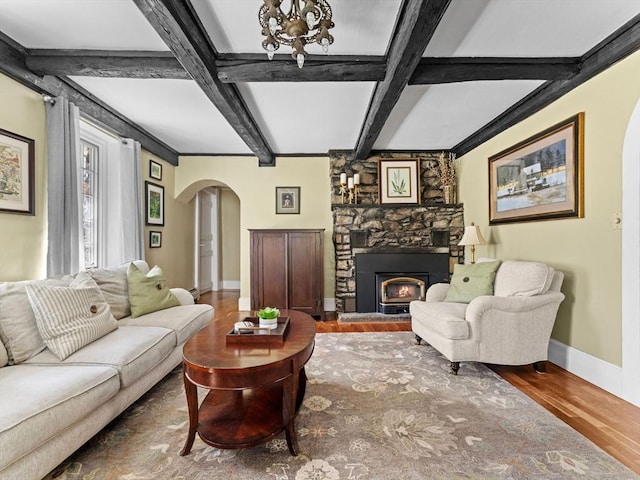 living room featuring wood finished floors, beamed ceiling, baseboards, arched walkways, and coffered ceiling
