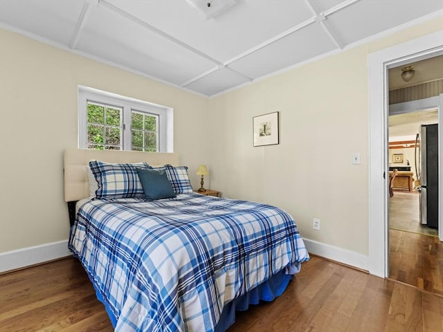 bedroom with freestanding refrigerator, baseboards, and wood finished floors