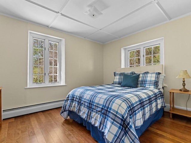 bedroom with crown molding, baseboards, baseboard heating, and hardwood / wood-style floors