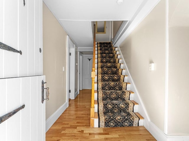 staircase featuring baseboards and wood finished floors