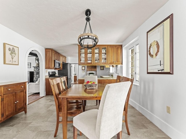 dining space featuring arched walkways, baseboards, and an inviting chandelier