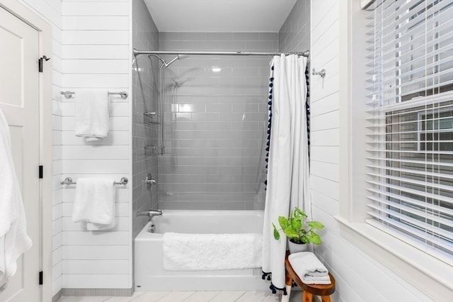 bathroom featuring wooden walls, tile patterned floors, and shower / bath combo with shower curtain