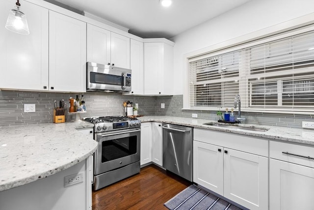 kitchen featuring white cabinetry, sink, stainless steel appliances, dark wood-type flooring, and pendant lighting