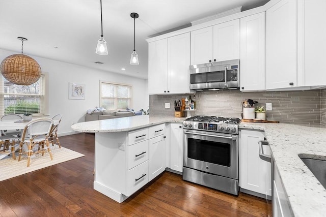 kitchen featuring white cabinets, appliances with stainless steel finishes, a wealth of natural light, and hanging light fixtures