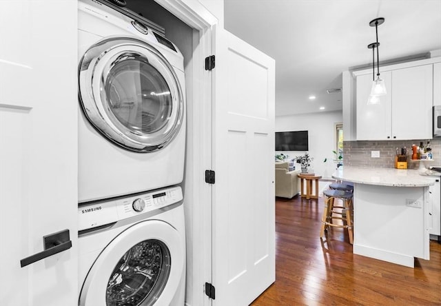 washroom featuring dark hardwood / wood-style flooring and stacked washer / dryer