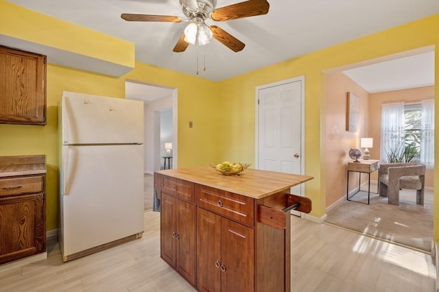 kitchen with ceiling fan, butcher block counters, white fridge, and a kitchen island