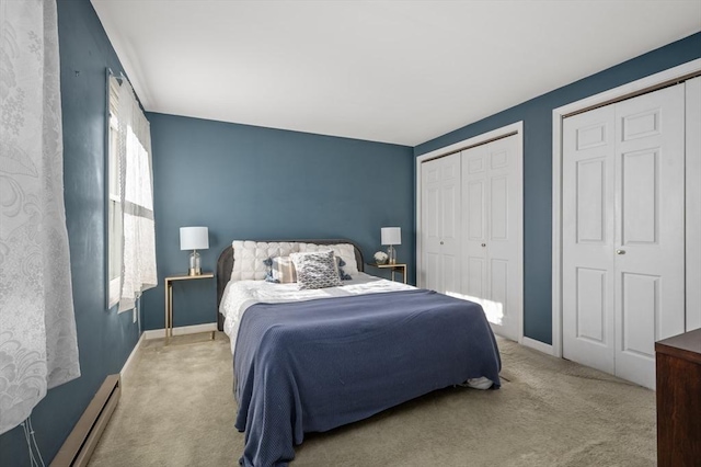 bedroom with light carpet, a baseboard heating unit, and two closets