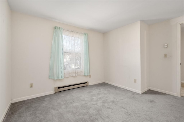 spare room featuring a baseboard heating unit and light colored carpet