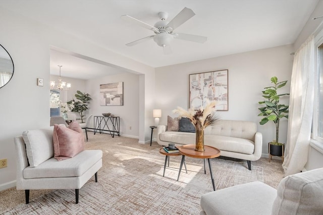 carpeted living room with ceiling fan with notable chandelier and plenty of natural light