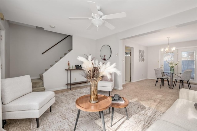 carpeted living room featuring ceiling fan with notable chandelier