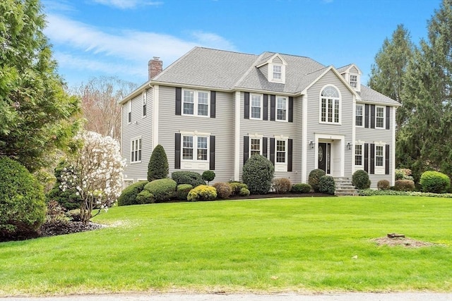 view of front of home featuring a chimney and a front lawn
