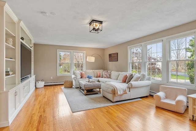 living area with light wood-type flooring, a baseboard radiator, a baseboard heating unit, and a wealth of natural light