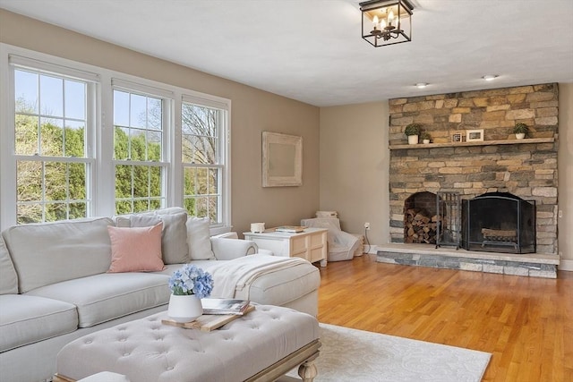 living area with a stone fireplace and wood finished floors