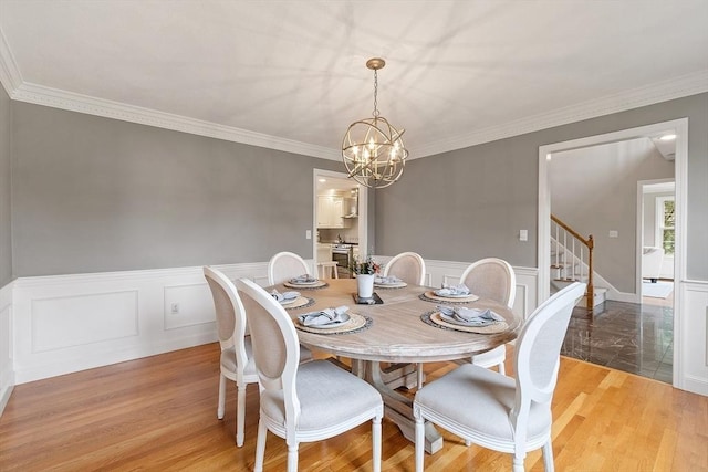 dining area featuring crown molding, a wainscoted wall, a notable chandelier, and stairway