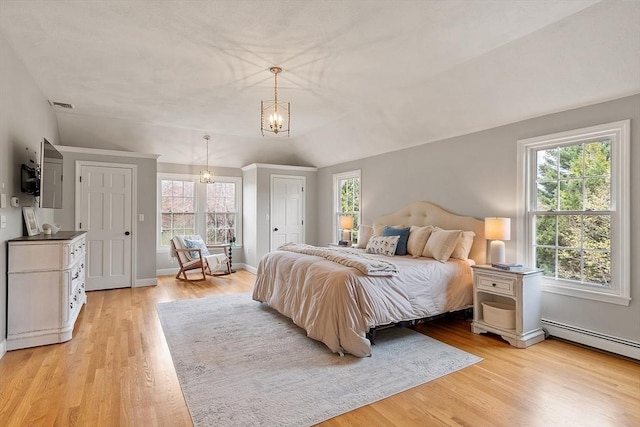 bedroom featuring visible vents, a notable chandelier, a baseboard heating unit, and light wood finished floors