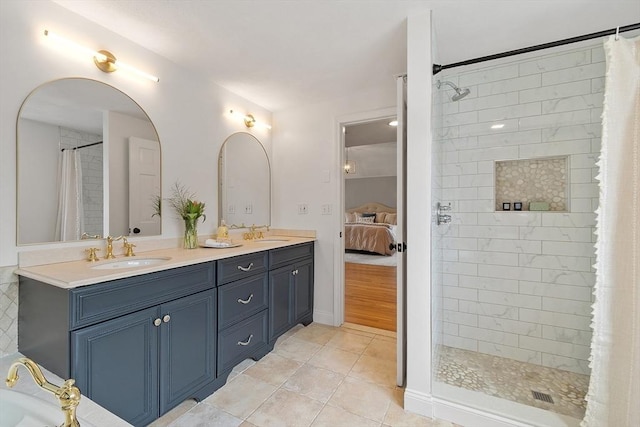 ensuite bathroom with double vanity, tile patterned floors, a tile shower, and a sink