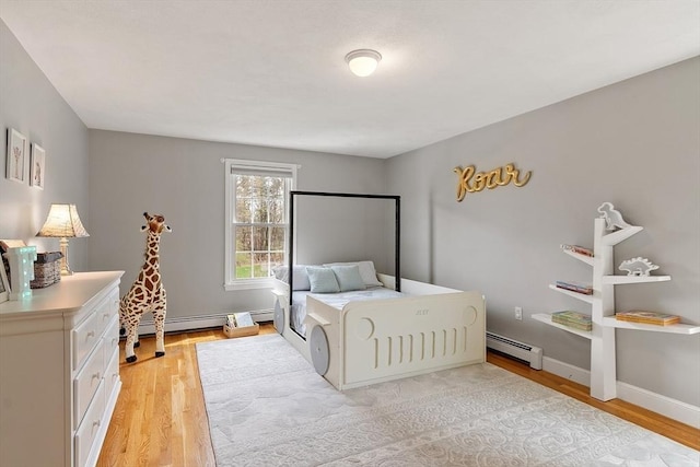 bedroom with a baseboard heating unit and light wood-style floors