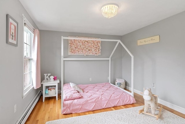 bedroom featuring baseboards, baseboard heating, and wood finished floors