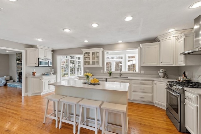 kitchen featuring white cabinets, a breakfast bar, a sink, light countertops, and stainless steel appliances