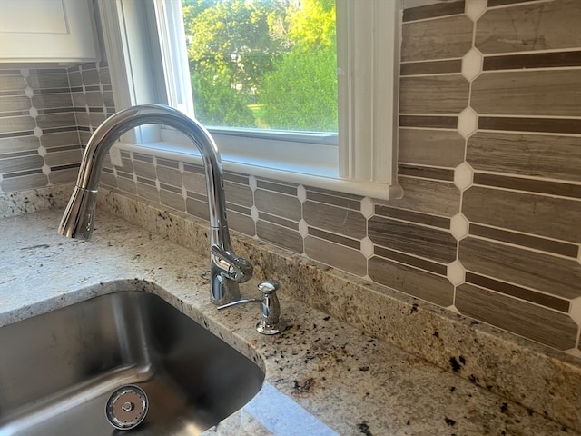 room details with light stone countertops, backsplash, and sink