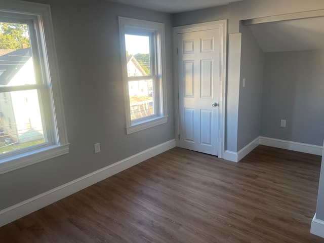 unfurnished bedroom featuring a closet, dark hardwood / wood-style flooring, and multiple windows