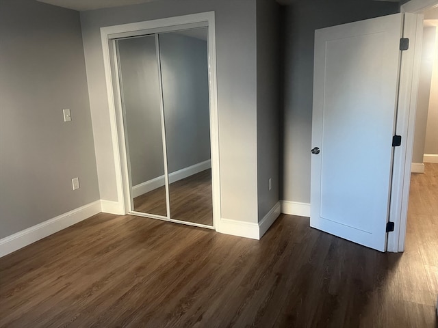 unfurnished bedroom with dark hardwood / wood-style flooring and a closet