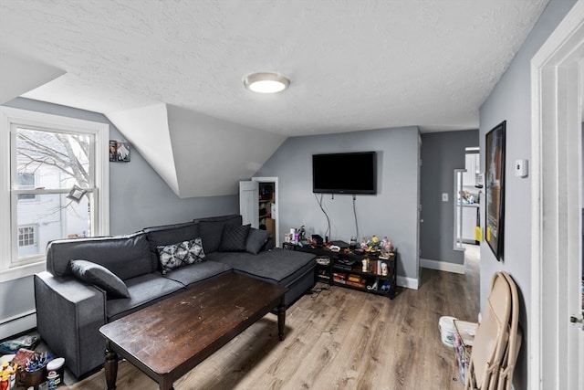 living room featuring a textured ceiling, lofted ceiling, baseboard heating, and hardwood / wood-style flooring