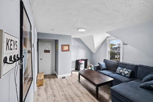 living room featuring a textured ceiling, light hardwood / wood-style floors, and vaulted ceiling