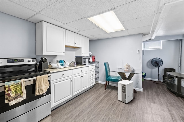 kitchen featuring appliances with stainless steel finishes, light hardwood / wood-style floors, white cabinetry, and a drop ceiling