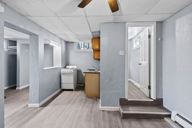 kitchen featuring light wood-type flooring, ceiling fan, baseboard heating, and white range oven